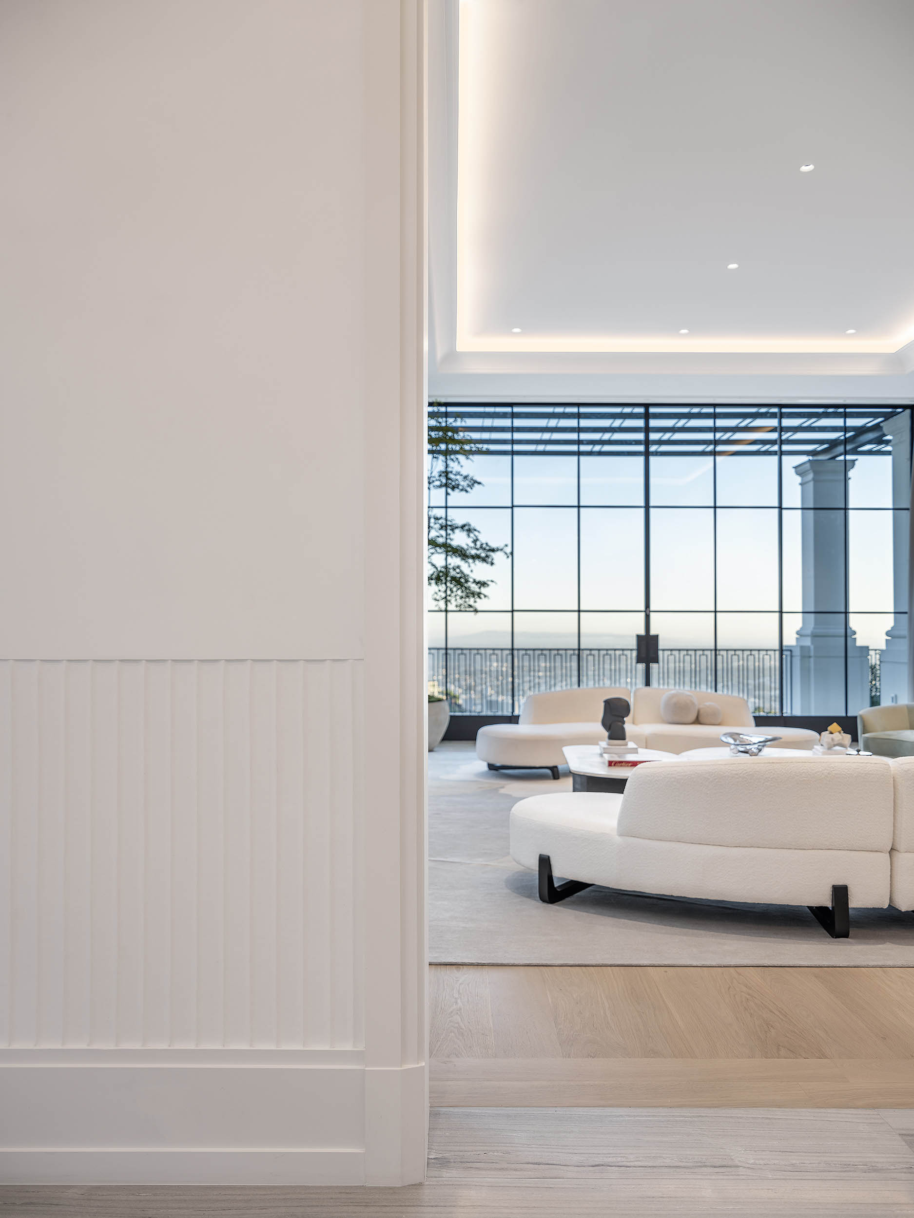 A spacious and elegantly designed living room from the Birds Street project by Coppel Design, featuring modern furnishings, artistic decor, and large windows that bring in abundant natural light.