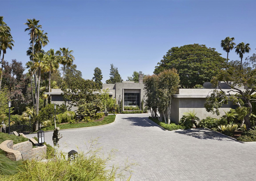 An elegant exterior view of a modern house designed by Coppel Design for the Hombly Hills project, showcasing clean lines, expansive glass windows, and stylish landscaping that harmonizes with the surrounding environment.