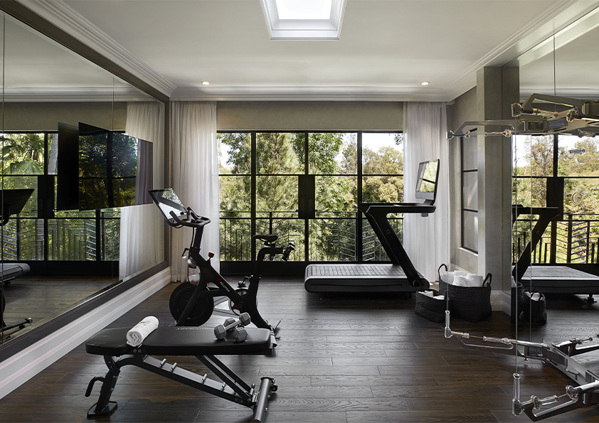 A modern gym designed by Coppel Design for the Hombly Hills project, featuring state-of-the-art fitness equipment, large windows that provide natural light, and a sleek, open layout that encourages an active lifestyle.