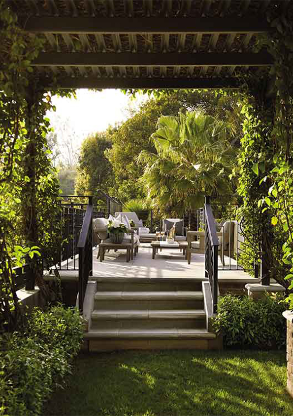 A serene garden view from the Hombly Hills project, designed by Coppel Design, featuring manicured landscaping, a modern patio with minimalist outdoor furniture, and lush greenery, all framed by clean architectural lines.